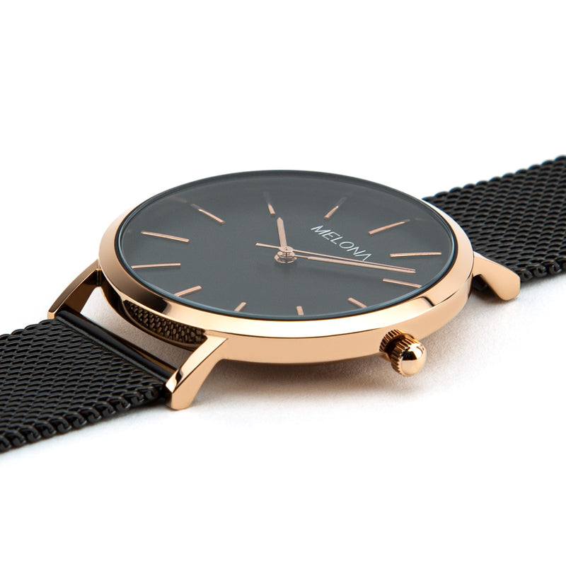 Reloj minimalista de mujer con correa de malla negra y detalles dorados de la marca de joyería española Melona. Colección Alma Mesh