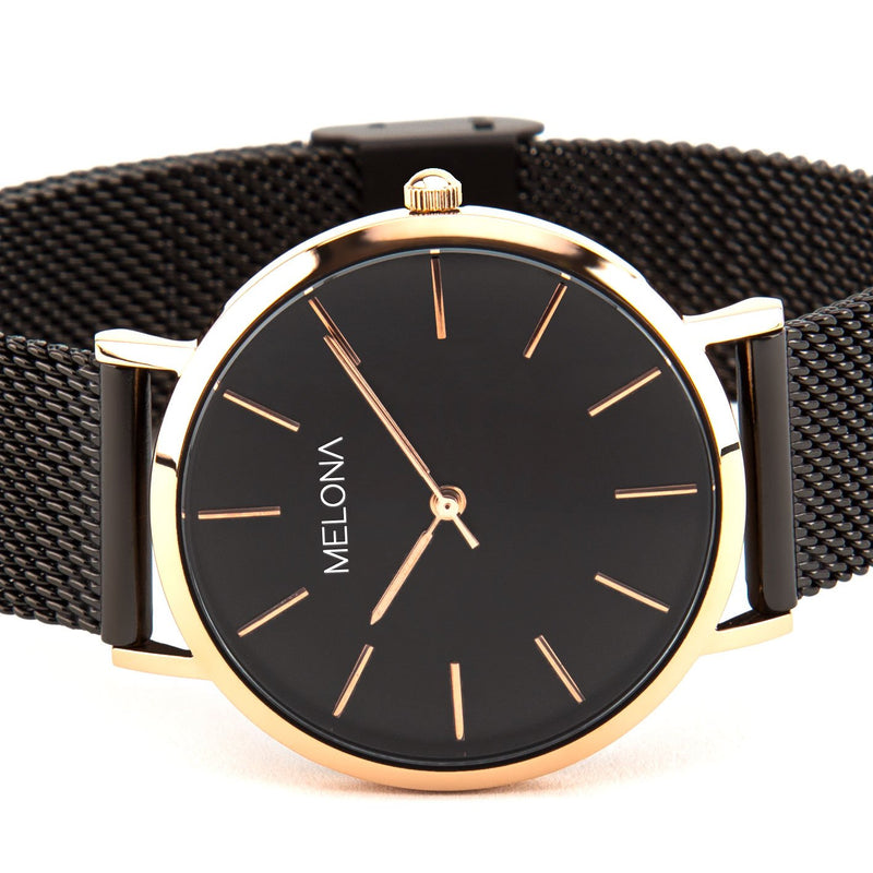 Reloj minimalista de mujer con correa de malla negra y detalles dorados de la marca de joyería española Melona. Colección Alma Mesh